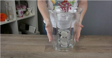Elle met un vase dans un autre et elle ajoute des cailloux. Quand elle verse de l’eau, la magie opère!