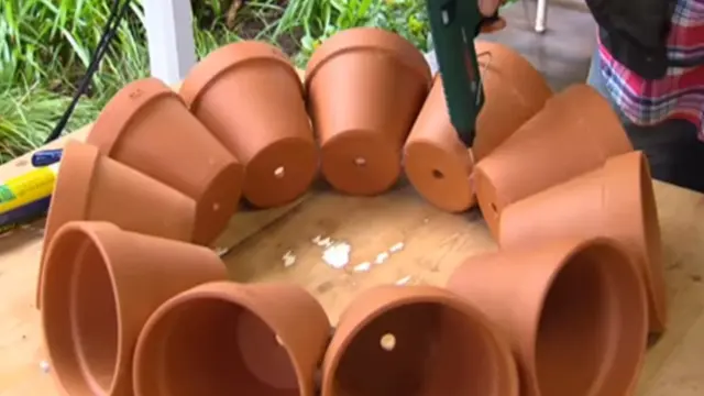 Il place 11 pots de fleurs en cercle sur une table et les colle ensemble